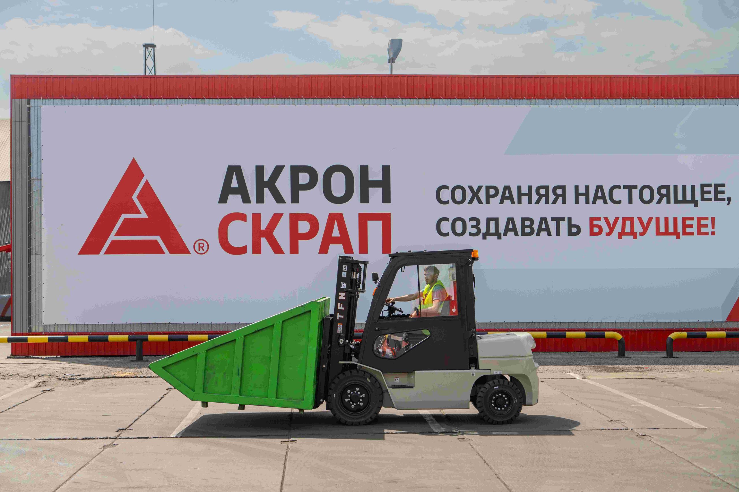 Вилочный погрузчик компании Акрон Скрап Металл на фоне фирменного баннера пункта приема лома